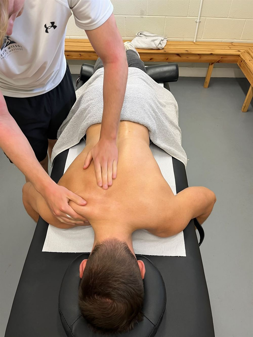 Lewis giving a back massage to a client on the treatment table
